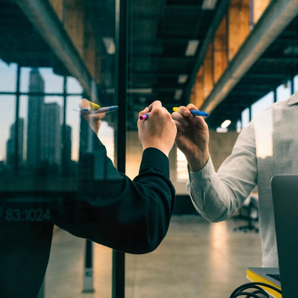 A small product team sketching architecture on a glass wall in a Chicago loft office